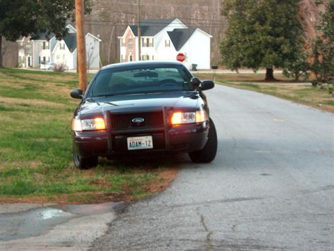 2001 Ford Crown Victoria - Front view of a 2001 Ford Crown Victoria police car parked on a street with houses in the background.