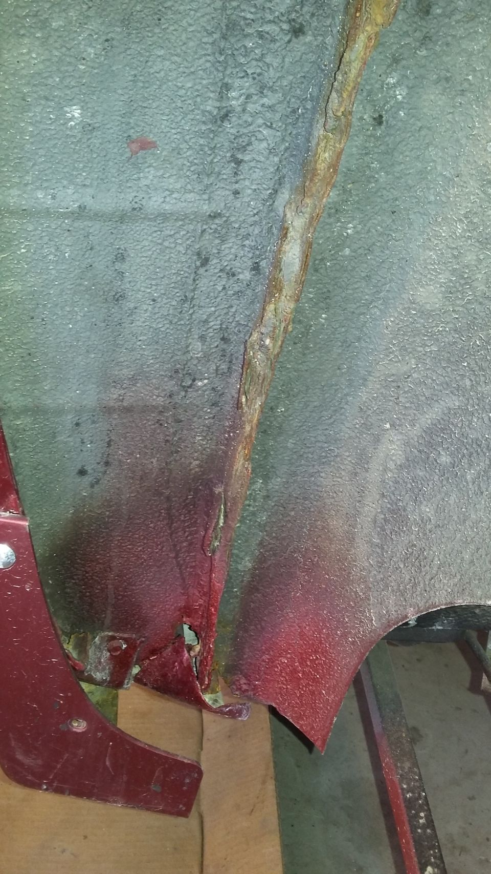 rusted metal on a car's undercarriage, red paint visible