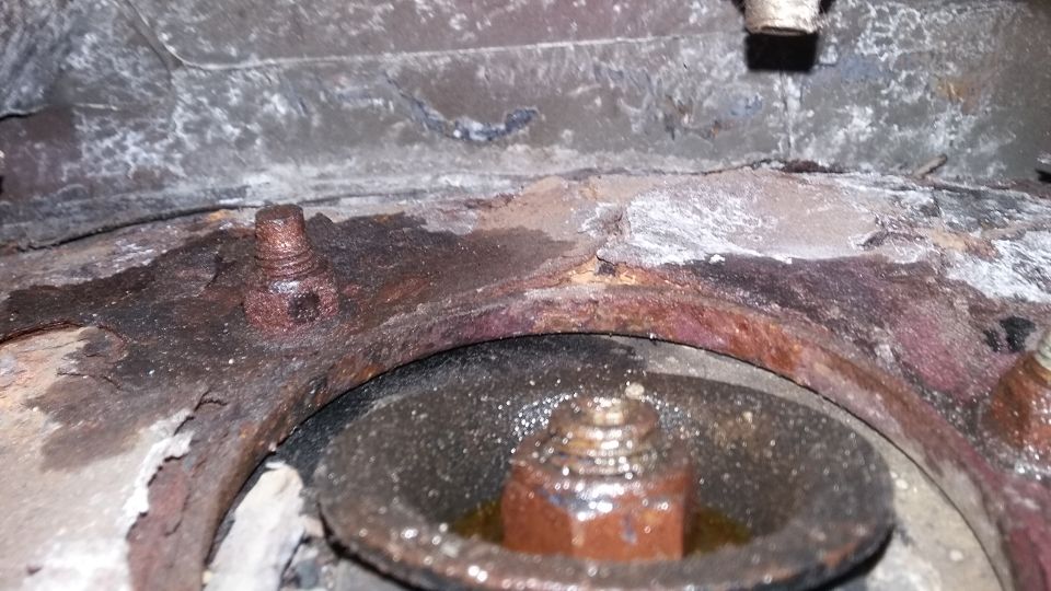 rusted metal bracket with bolts and a circular component below