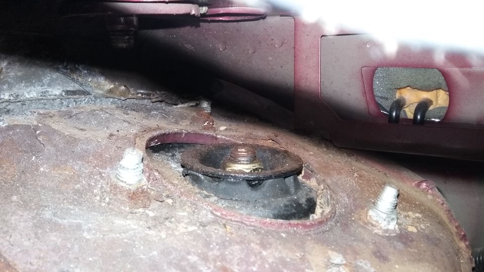 Close-up of a rusty vehicle strut mount with bolts