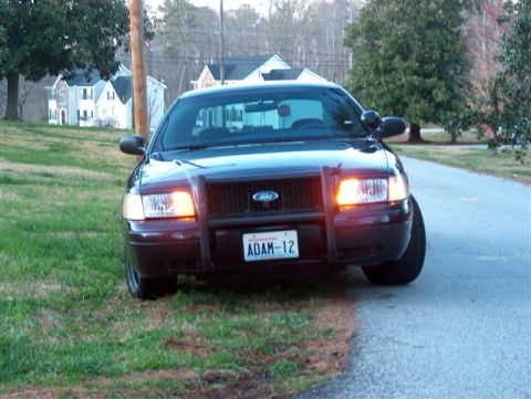 2001 Ford Crown Victoria - Front view of a 2001 Ford Crown Victoria police car with a push bumper, parked on the side of a road.