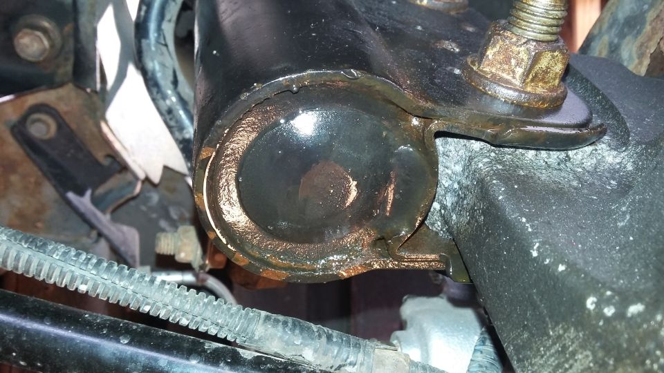 Close-up of a corroded automotive suspension bushing with visible rust and grease