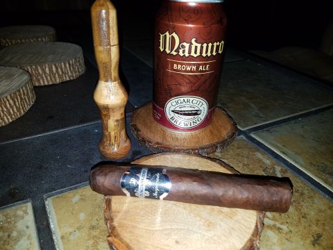 2018 Ford Bronco - A cigar and a can of Maduro Brown Ale are displayed on wooden coasters, with a wooden tool in the background.