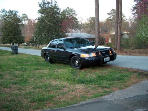 2001 Ford Crown Victoria - A black 2001 Ford Crown Victoria police car is parked on the side of a residential street.