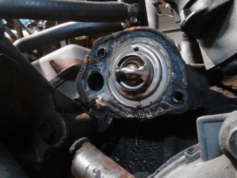 1995 Ford Bronco - Close-up of a vehicle's engine thermostat housing, showing the thermostat itself.