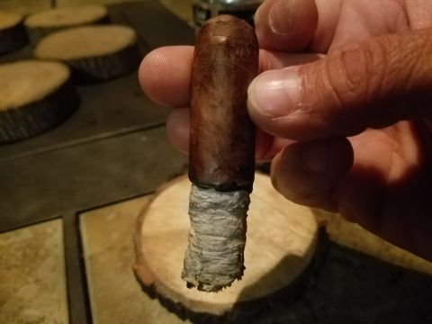 2018 Ford Bronco - A cigar is held by fingers, with wooden discs in the background.