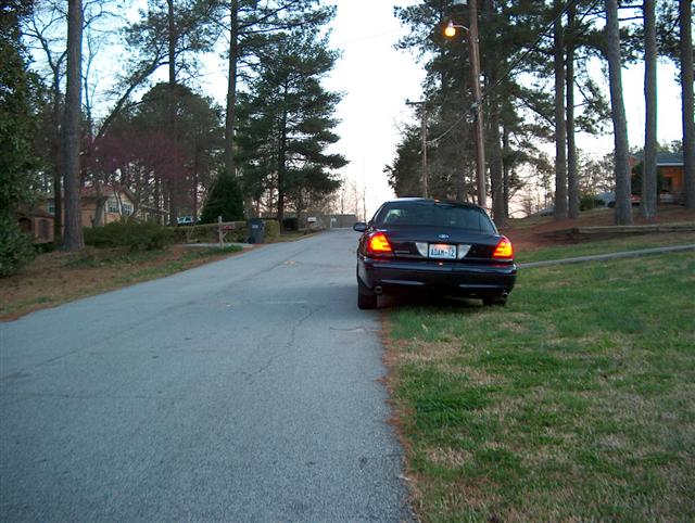 2001 Ford Crown Victoria parked on the side of a road, rear view. License plate reads ADAN-12