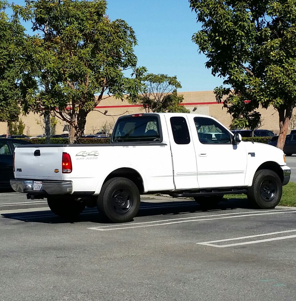 White 1999 Ford F-150 XLT SuperCab 4x4 pickup truck parked in a lot