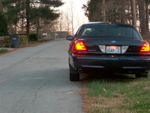 2001 Ford Crown Victoria - The rear of a black 2001 Ford Crown Victoria is parked on the side of a residential road.