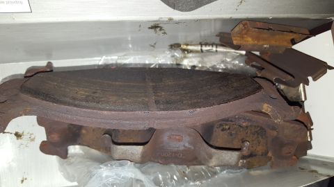 1967 Ford Bronco - Close-up view of heavily worn brake pads and a rotor, showing significant rust and material loss.