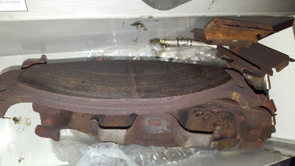 Worn brake pads and rotor assembly with visible rust and wear