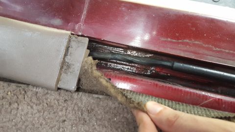 1967 Ford Bronco - A hand cleans the weathered door seal and surrounding area of a vehicle's interior.