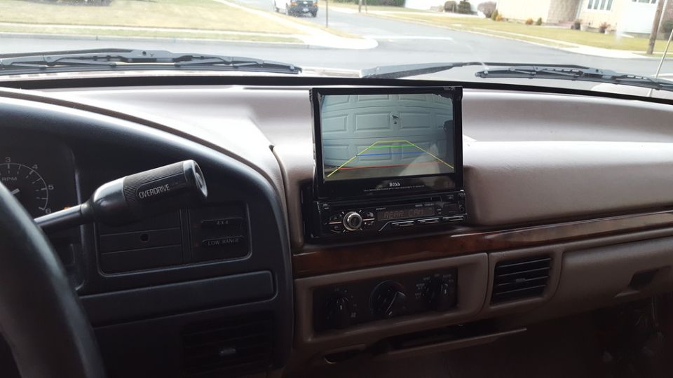 Vehicle interior dashboard with a backup camera screen showing a garage door