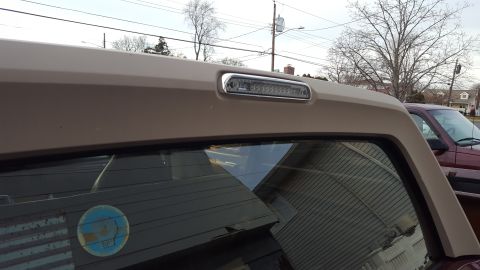 1967 Ford Bronco - Close-up of a tan SUV's rear window and roofline, a modern LED third brake light.