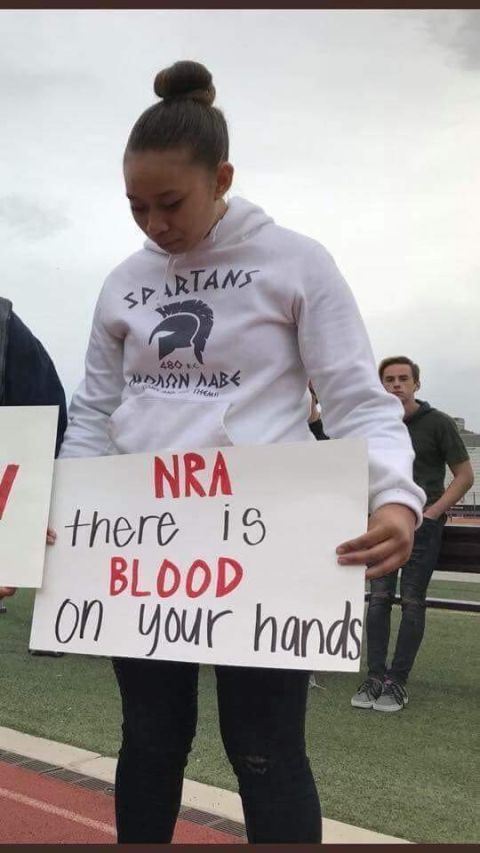 1965 Ford Mustang - A young person holds a sign with a political message during an outdoor gathering.