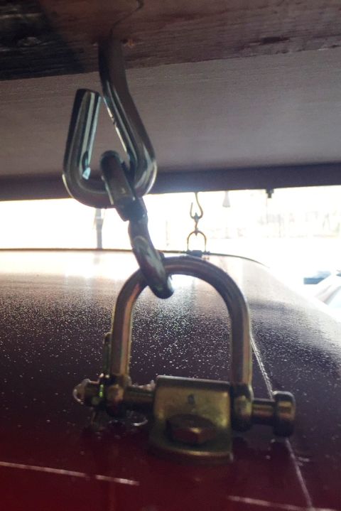 1994 Ford Bronco - A metal hook and chain assembly is attached to the roof of a red vehicle.