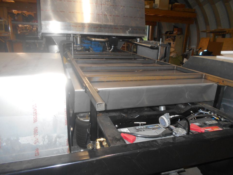 Underside view of a vehicle chassis with engine components and battery visible