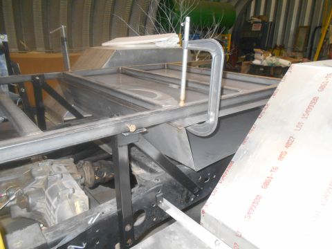 1992 Ford Bronco - A vehicle's chassis and transmission are visible, undergoing fabrication with metal framing and a clamp.