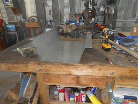 1992 Ford Bronco - A metal part is on a workbench, surrounded by tools and various supplies, in what appears to be a workshop.