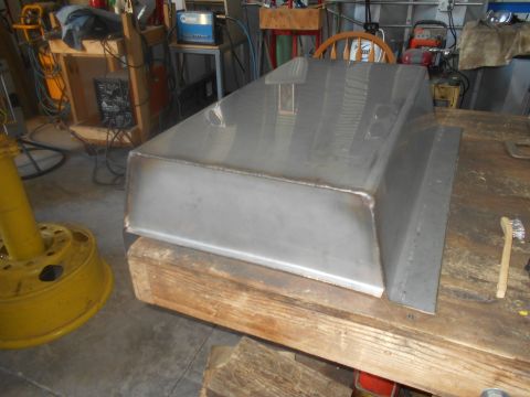 1992 Ford Bronco - A custom metal part sits on wooden blocks in a workshop setting, with welding equipment visible in the background.