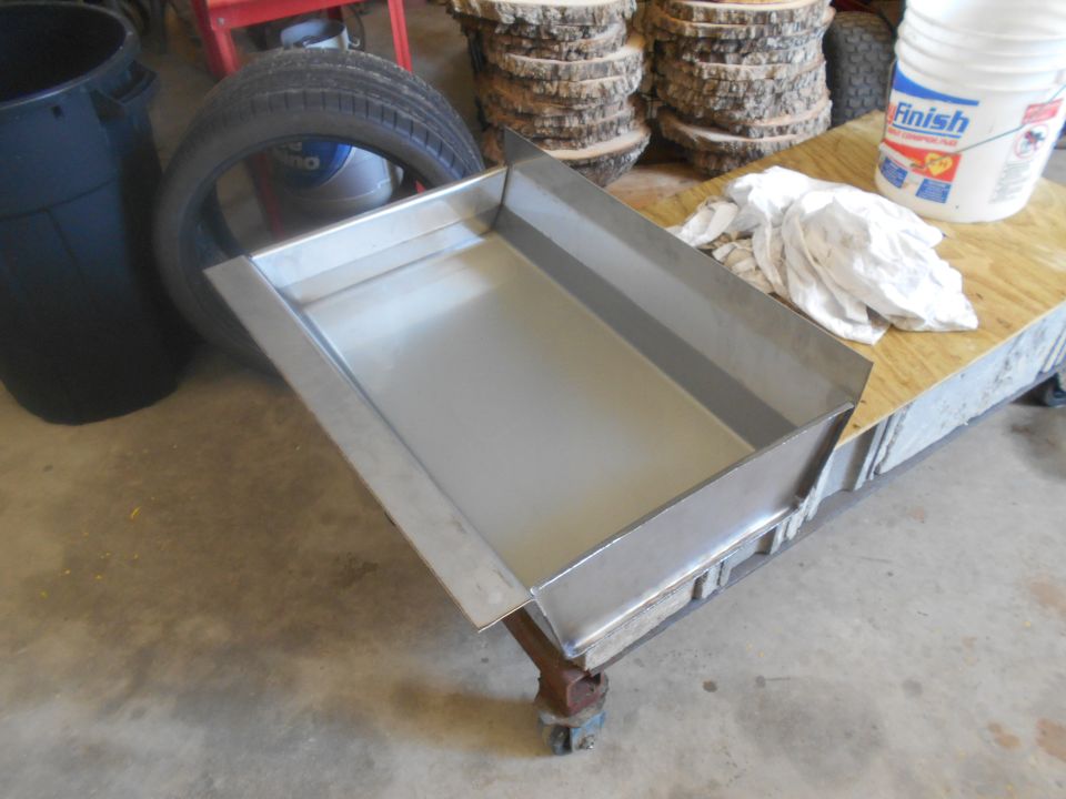 Metal drip pan on a workbench next to a tire and bucket