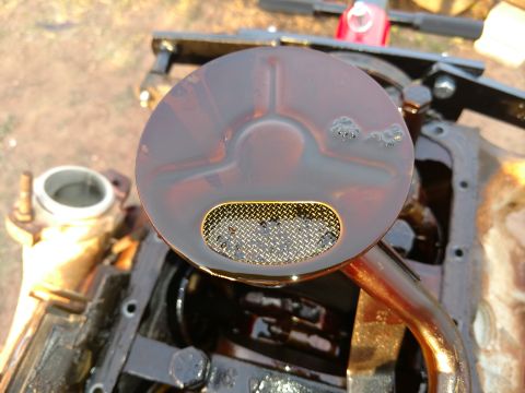 1996 Ford Bronco - Close-up of an engine's oil pan and pickup tube, showing accumulated grime and oil.