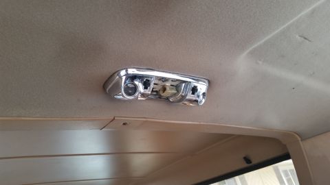 1985 Ford Bronco - A close-up view of a chrome interior dome light fixture mounted on the headliner of a vehicle. The fixture appears to be missing its bulbs…