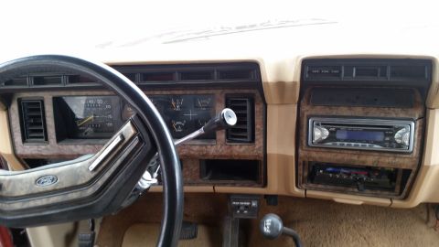 1985 Ford Bronco - Interior dashboard of a Ford truck showing the gauge cluster, steering wheel with Ford emblem and an aftermarket JVC stereo head unit.