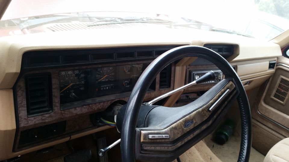 Interior of a vintage Ford Bronco or truck, showing dashboard, steering wheel, and gauges.
