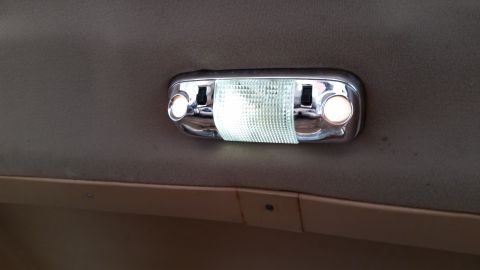 1985 Ford Bronco - A close-up interior shot shows a chrome-trimmed dome light with two bulbs and a textured plastic lens, mounted on the headliner of a vehicl…