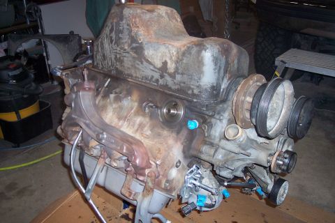 1995 Ford Bronco - A heavily rusted V8 engine block is shown in a workshop setting. The engine has several pulleys attached to the front and an exhaust manifo…