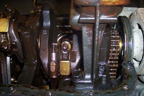 1995 Ford Bronco - A close-up view of the internal components of an engine, likely a crankshaft and connecting rods, covered in oil. A timing chain is visible…