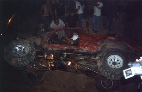2000 Ford F-450 - An off-road vehicle has rolled onto its side, attracting a crowd of onlookers.
