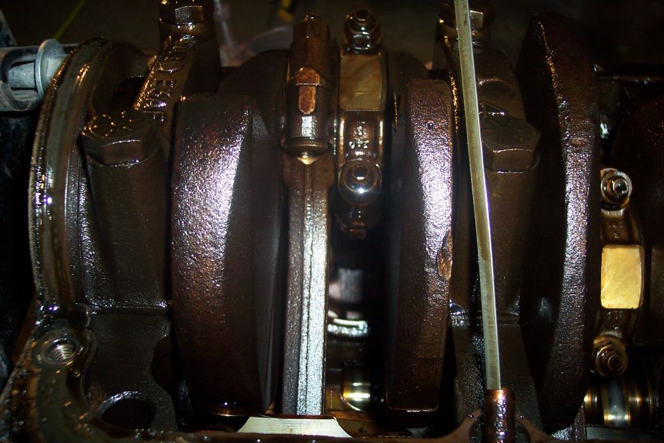 Close-up of engine crankshaft and connecting rods with oil.