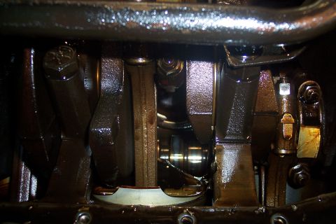 1995 Ford Bronco - Close-up view of the crankshaft and connecting rods of a V8 engine, coated in oil. The metal components show signs of wear and are lubricat…