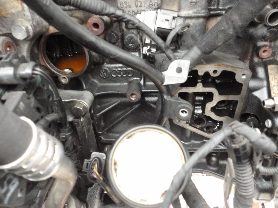 Close-up of a dirty diesel engine block with internal components, hoses, and wiring.