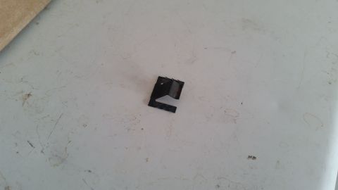1985 Ford Bronco - A small, black metal clip with three prongs is shown resting on a textured white surface. The clip appears to be a replacement part for a v…
