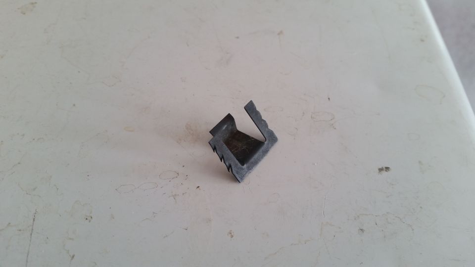 Small, dark gray, L-shaped metal bracket with serrated edges