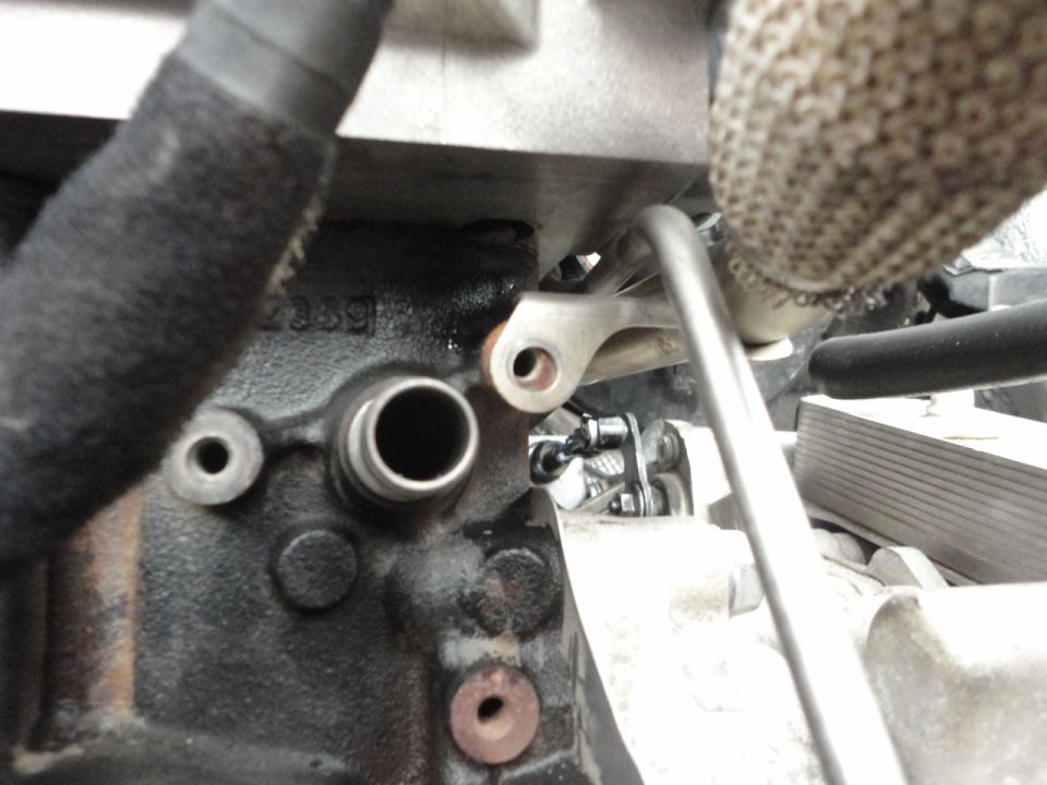 Close-up of a vehicle engine block with metal components and hoses.