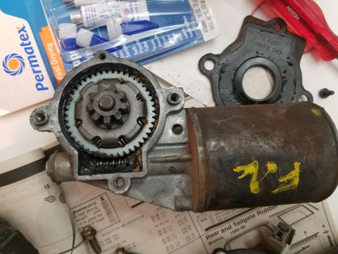1967 Ford Bronco - A disassembled power window motor assembly is laid out on a document with various Permatex adhesive tubes and a red screwdriver in the back…