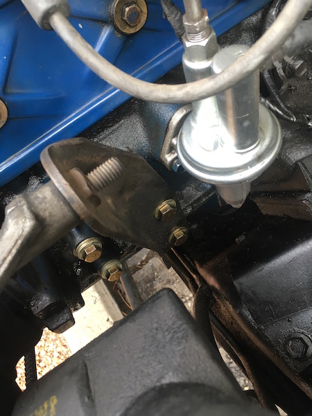 1981 Ford Bronco - A close-up view of a mechanical fuel pump mounted to the engine block of a vehicle. The fuel pump is silver and connected to fuel lines, wi…