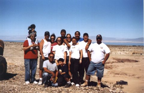 2000 Ford F-450 - A group of people gathered in a desert landscape under a clear blue sky.