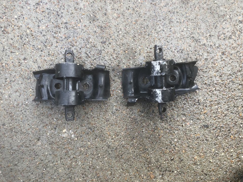 Two black engine mounts on a wet concrete surface