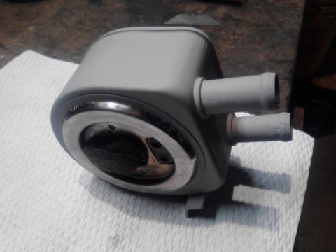 1995 Ford Bronco - A gray painted vehicle part, possibly a heater core or radiator, with two hose connections and a circular opening with visible internal com…