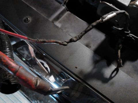 1995 Ford Bronco - A close-up view shows a damaged red wire harness with exposed copper and black electrical tape, connected to a larger red cable with a meta…