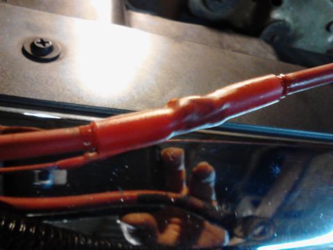 1995 Ford Bronco - A close-up view shows a red insulated wire with a crimped connection, possibly part of a vehicle's electrical system. The wire is positione…