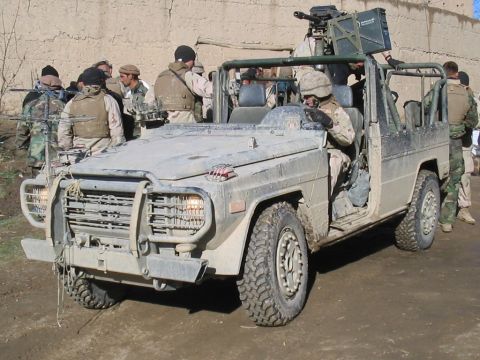 1981 Ford Bronco - A military vehicle, possibly a modified Mercedes-Benz G-Wagen, equipped with a machine gun, is seen with soldiers around it.