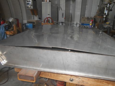 1992 Ford Bronco - A large, bent, stainless steel rectangular object is supported by wooden beams in a workshop. The object appears to be a custom-fabricated…