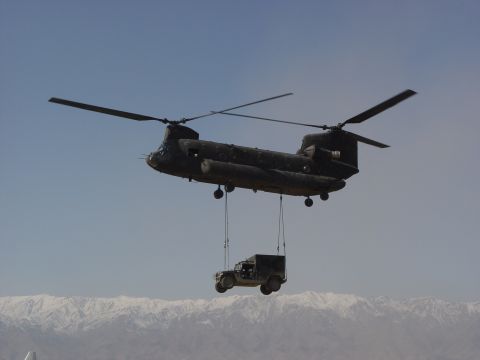 1981 Ford Bronco - A Chinook helicopter transports a Humvee in a mountainous region.