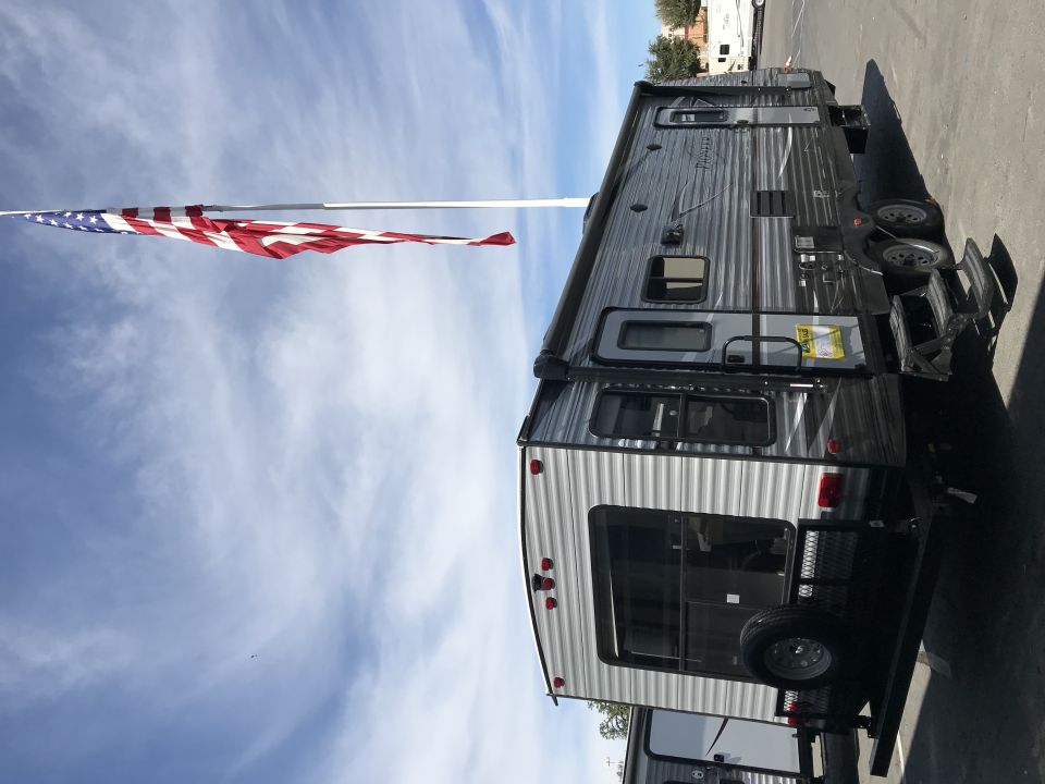 Travel trailer parked outdoors with American flag flying.